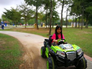 Girl riding beach buggy on footpath at park