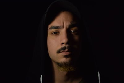 Close-up portrait of young man against black background