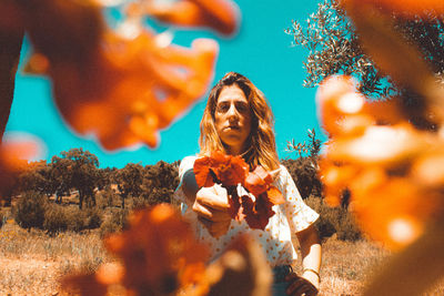 Portrait of young woman holding plants