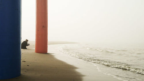 Man standing on beach by sea against sky