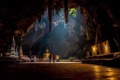 People walking in temple under cave