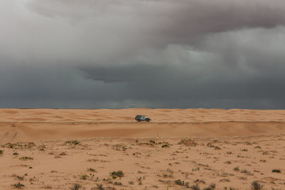 Lone car under stormy rain clouds during a microburst in the desert