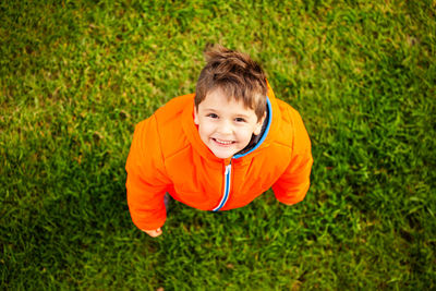 High angle portrait of smiling boy standing on grass