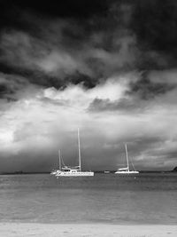 Sailboat sailing in sea against cloudy sky