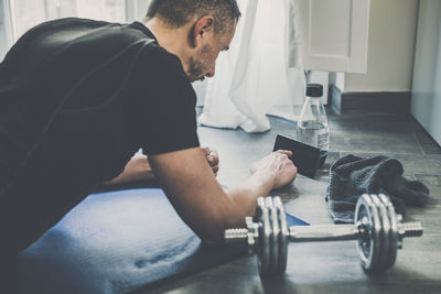 Sporty man resting after working out at home. boy looking exercise video online in the living room. 