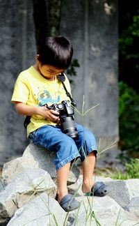 Full length of boy sitting on rock