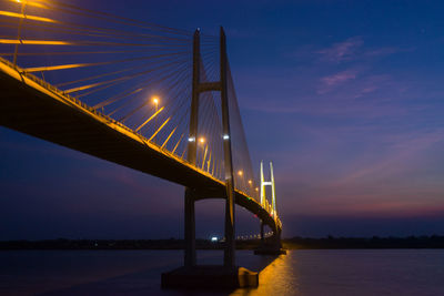 Illuminated bridge over river against sky at sunset