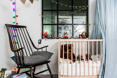 Empty chair by crib with decorations at home