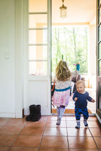 Full length of siblings at home entrance