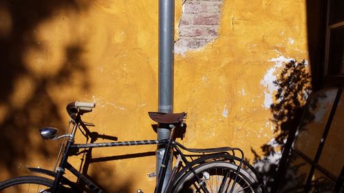 Close-up of bicycle parked against yellow window
