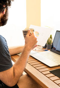 Midsection of man using mobile phone while sitting on table