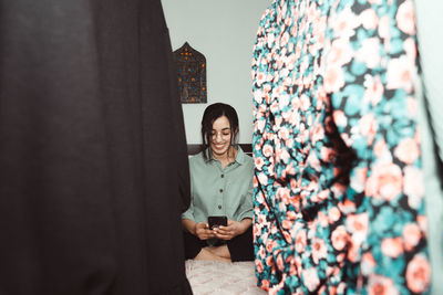 Portrait of smiling young woman standing against wall