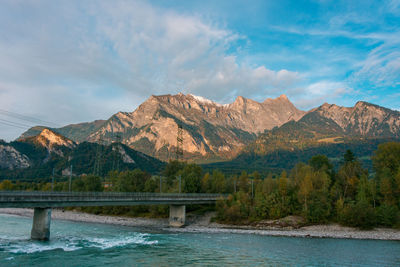 Scenic view of river by mountains against sky