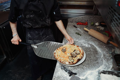 Midsection of man preparing pizza