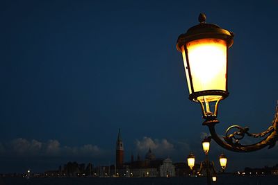 Illuminated street light against sky in city at night