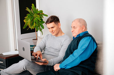 Man teaching laptop to grandfather at home