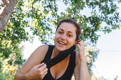 Portrait of smiling young woman against trees