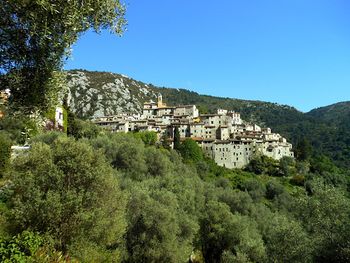 Scenic view of townscape by mountains against clear blue sky