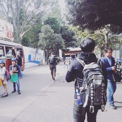 Rear view of people walking on street in city