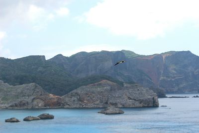 Scenic view of sea by mountains against sky