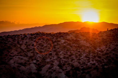 Scenic view of silhouette mountains against orange sky