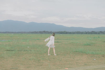 Rear view of man standing on field against sky