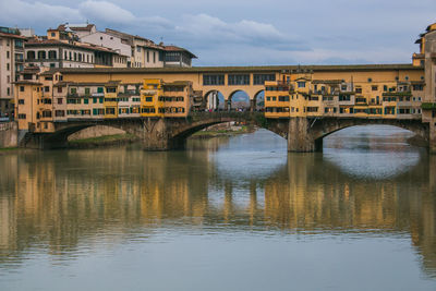 View of the historic ponte vecchio with gorgeous reflections in the arno river during winter season