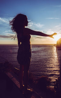 Woman looking at sea against sky during sunset