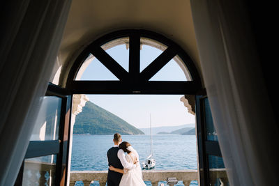 Rear view of man and woman standing by window