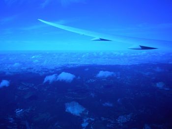 Close-up of airplane flying over sea against blue sky