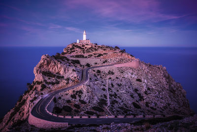 Panoramic view of illuminated building by sea against sky