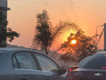 Cars on street against sky during sunset