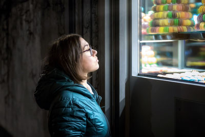 Side view of woman looking at macaroons on window display