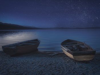 Boat moored on beach against sky at night