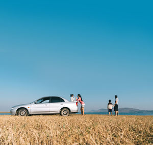 People by car against blue sky