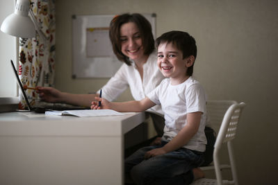 Happy mother is engaged in a laptop with her son preschooler, a real european interior, the concept 