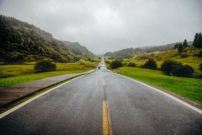 Road leading towards mountains against sky