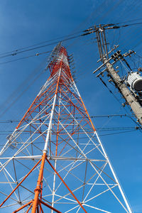 Low angle view of electricity pylon against blue sky