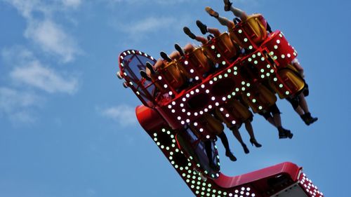 Low angle view of people on ride against sky