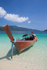 Boat moored on beach against sky