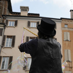 Rear view of man holding umbrella against building