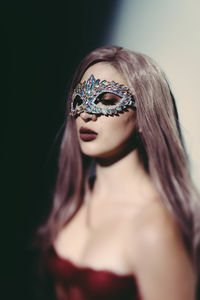 Portrait of woman wearing mask against black background