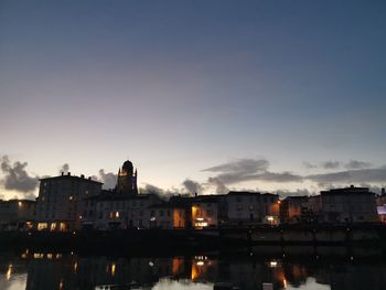 Illuminated buildings against sky at sunset