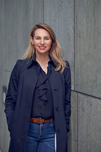 Portrait of smiling woman standing by wall