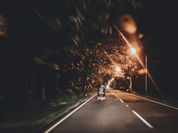 Man riding illuminated on road at night