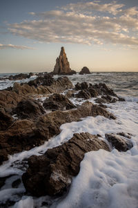 Rock formations on shore against sky during sunset