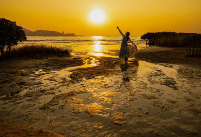 Man standing on beach against sky during sunset