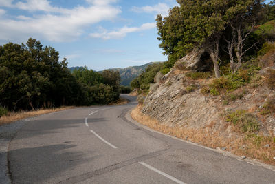 Empty country road against cloudy sky