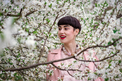 Portrait of young woman with pink cherry blossoms in spring