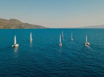 Sailboats in blue turquoise sea against clear sailing in fleet in summer mediterranean destination.